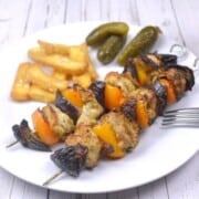 Juicy oven cooked chicken kebabs served on a plate with crispy fries and pickles.