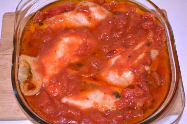 Chopped Tomatoes Canned chopped tomatoes with juices poured over braised chicken legs and peppers in a casserole dish.