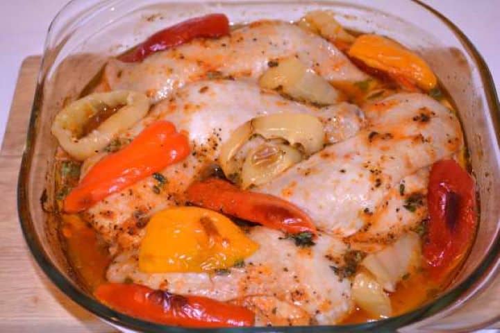 Half Cooked Half-cooked, juicy chicken legs and softened bell peppers in a glass dish after removing the aluminium foil.
