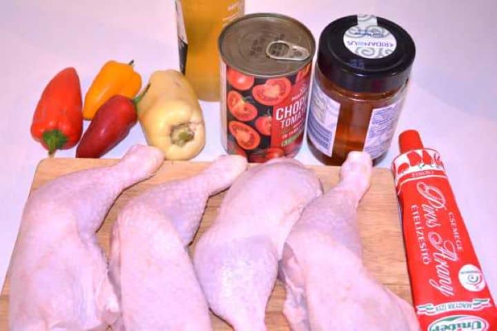 Ingredients Raw chicken legs, sweet bell peppers, sweet paprika paste, honey, beer, and canned tomatoes on a countertop.