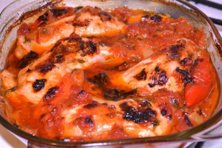 Ready Tender roasted chicken legs with a bubbling, reduced sweet pepper, tomato, and beer sauce in a glass baking dish.
