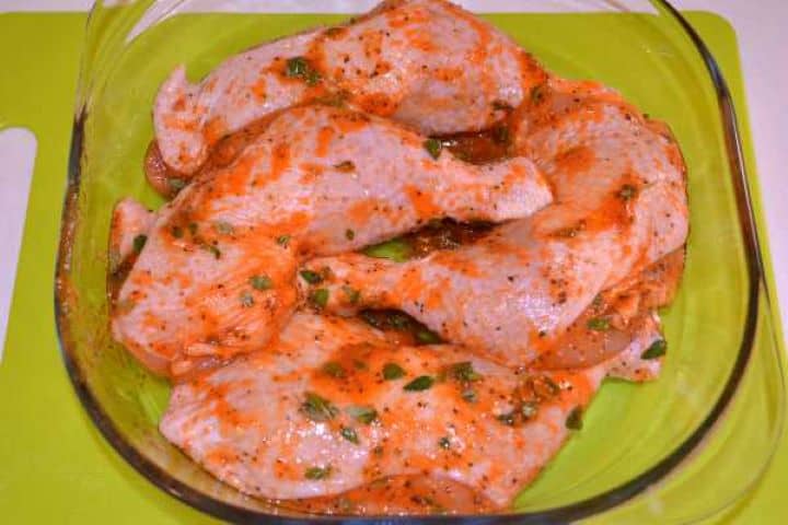 Legs in Casserole Raw seasoned chicken legs arranged in a single layer in a glass casserole dish with sunflower oil.