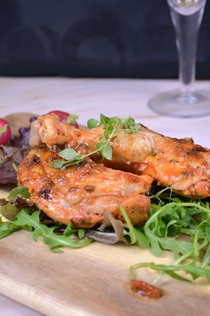 Serve Juicy roasted chicken legs served on a wooden board with fresh wild rocket and sliced radishes.