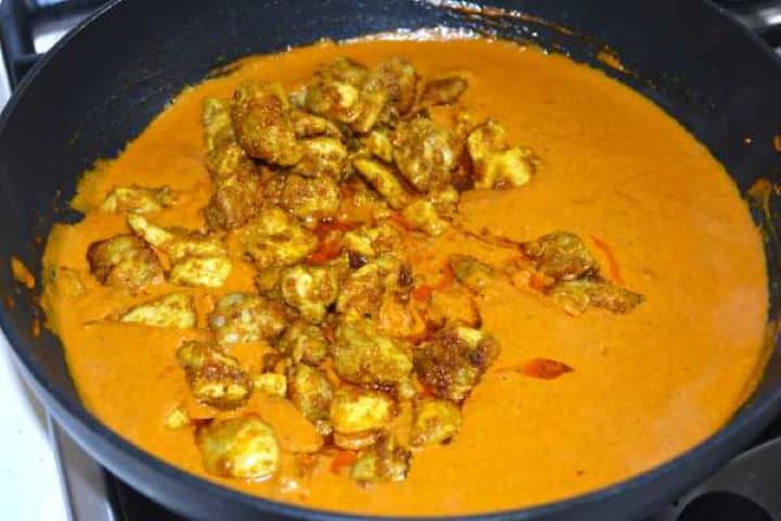 Simmering cooked chicken thighs in a smooth tomato cream sauce with melted butter.
