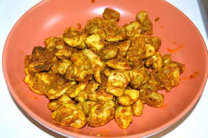 Golden-brown cooked chicken thighs resting on a plate before adding to the sauce.