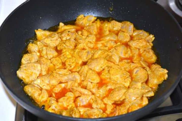 Searing yogurt-marinated chicken thighs in a pan over medium-high heat.