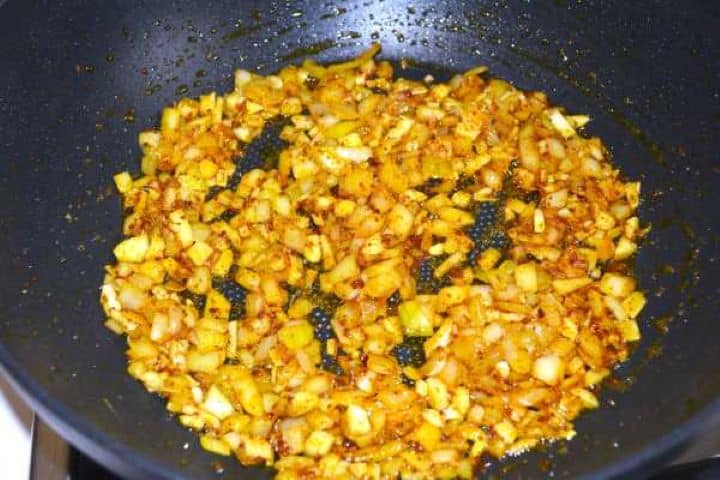 Sautéing diced yellow onions, fresh garlic, and ginger in butter.