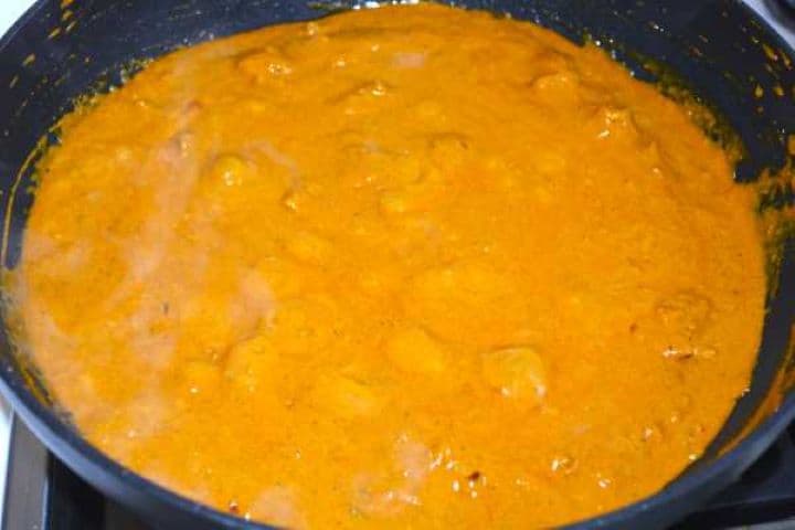 Freshly cooked creamy butter chicken simmering in a wok pan.