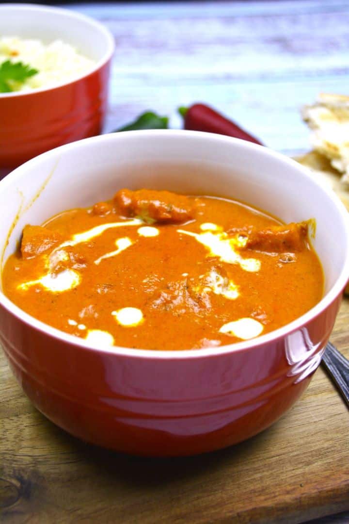 Restaurant-style creamy butter chicken garnished with heavy cream and chili flakes.
