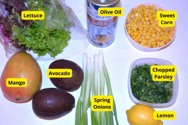 Ingredients Fresh ingredients for avocado mango salad: ripe avocados, sweet mango, sweet corn, spring onions, lemon, and parsley.