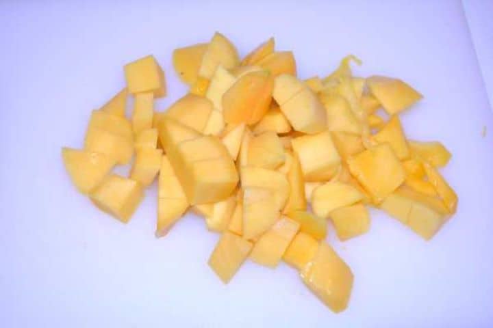 Cut Mango Freshly diced sweet mango cubes on a white chopping board.