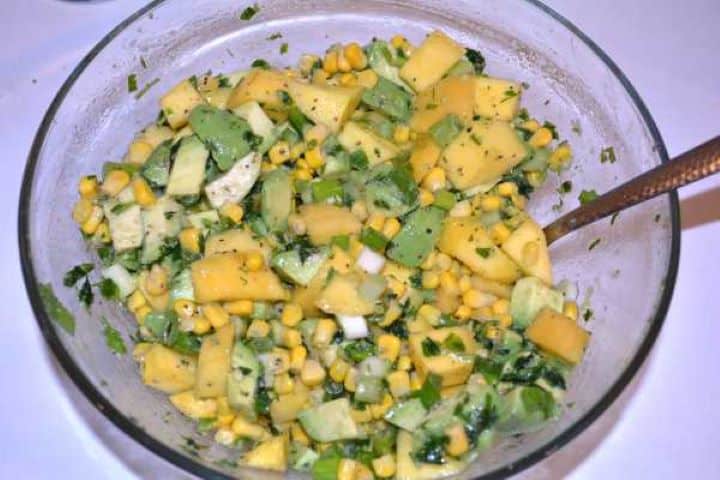 Mixed Ingredients Gently mixed easy avocado and mango salad in a glass bowl ready to chill.