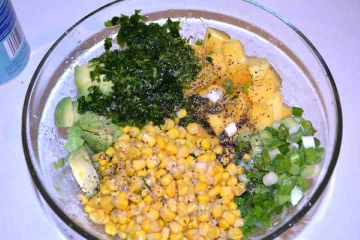 Seasoning Squeezing fresh lemon juice and adding olive oil and pepper over avocado mango salad ingredients.