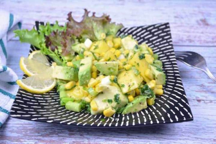 Serve Plated easy avocado and mango salad garnished with lemon slices on a bed of crisp lettuce.
