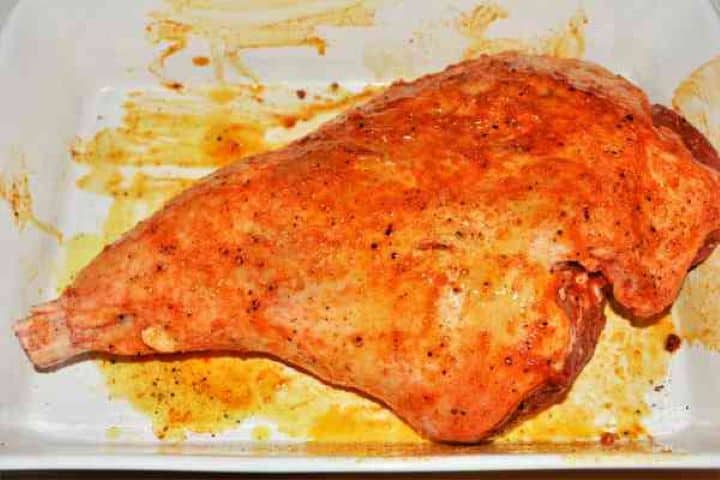 Slow Roasted Leg of Lamb Recipe-Seasoned Lamb Leg Leg of lamb seasoned with paprika, garlic powder, and olive oil in a ceramic roasting tray.