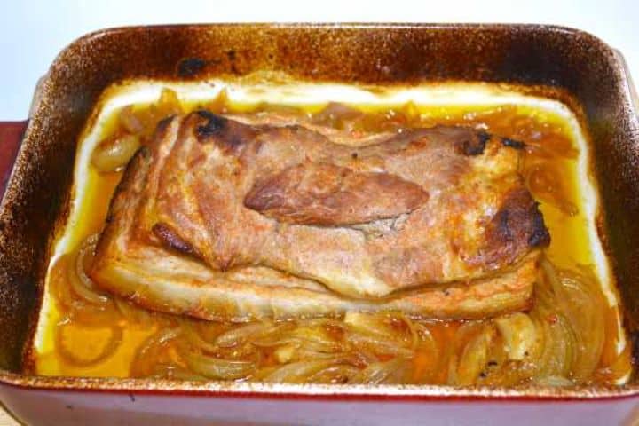 Braised pork belly turned over halfway through cooking in the roasting dish.