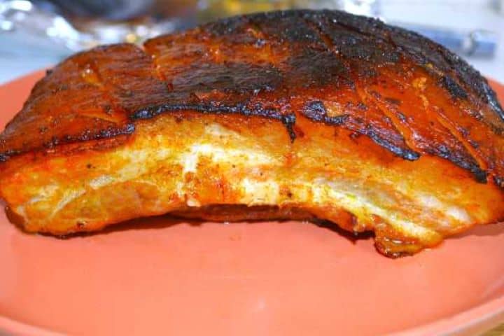 Slow roasted sticky honey glazed pork belly served on a rustic plate with bread.