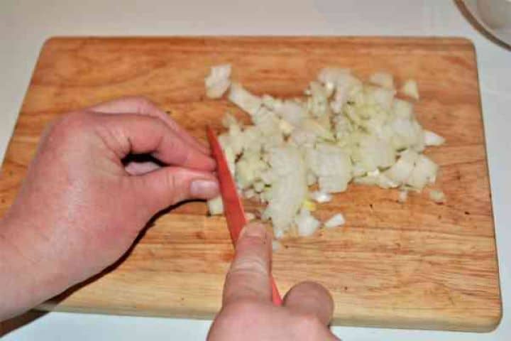 Best Mushroom Soup Recipe-Chopped Onions Finely diced yellow onion on a cutting board.