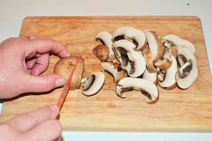 Best Mushroom Soup Recipe-Slicing the Mushrooms Slicing fresh chestnut mushrooms on a wooden cutting board for Hungarian soup.