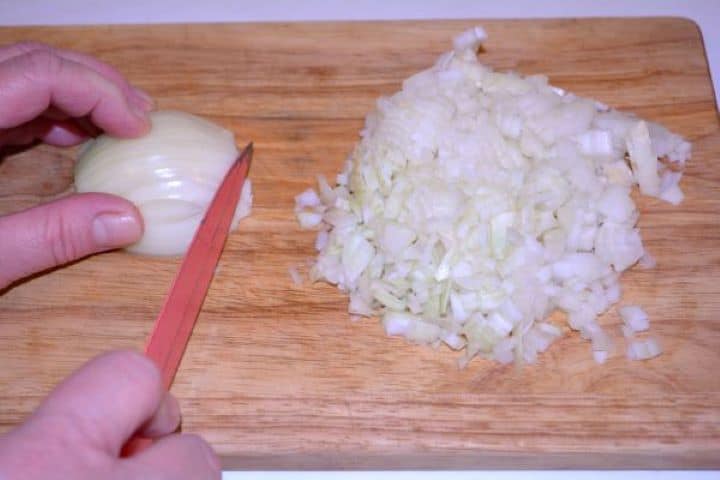 Layered Sauerkraut Casserole-Chopping the Onions Dicing yellow onions finely on a wooden cutting board for the casserole layers.