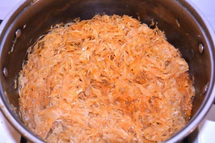 Softened cooked sauerkraut seasoned with summer savory and ground caraway in a pot.