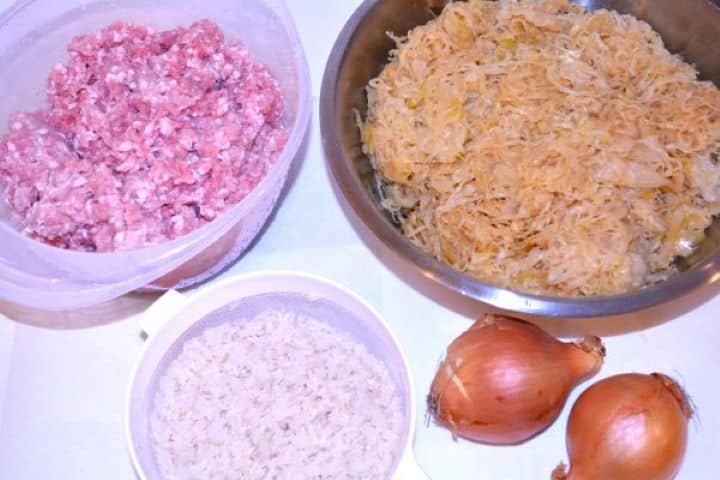 Layered Sauerkraut Casserole-Pork Mince, Sauerkraut, Rice and Onions Ingredients for layered sauerkraut casserole including minced pork, shredded sauerkraut, uncooked rice, and yellow onions.