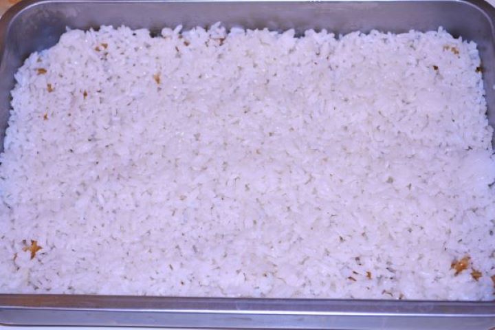 Layered Sauerkraut Casserole-Rice is the Second Layer in the Baking Dish Spreading the second layer of cooked white rice over the sauerkraut in the baking pan.