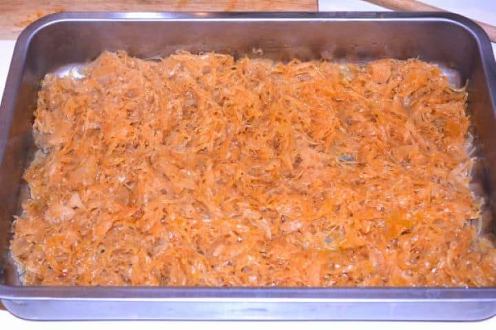 Layered Sauerkraut Casserole-Sauerkraut is the First Layer in the Baking Dish Spreading the first layer of sautéed sauerkraut evenly across the bottom of a greased baking dish.