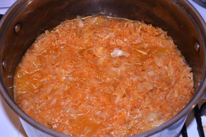 Layered Sauerkraut Casserole-Simmering Sauerkraut in the Pot Simmering shredded sauerkraut with water and herbs uncovered in a soup pot.