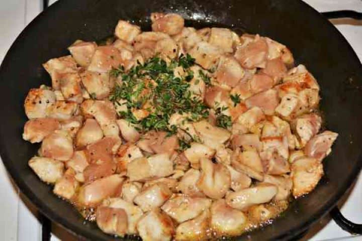 Chicken Breast With Pineapple-Seasoning With Thyme the Frying Chicken Cubes in the Pan Adding fresh chopped thyme leaves to frying chicken breast in the pan.