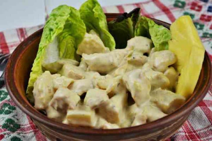 Chicken Breast With Pineapple-Served in Bowl Garnished With Lettuce and Pineapple Slices Close-up of cold creamy pineapple chicken salad served on crisp lettuce leaves alongside crusty artisan bread.