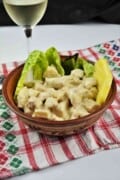 Close-up of cold creamy pineapple chicken salad served in ceramic bowl on crisp lettuce leaves alongside crusty artisan bread.