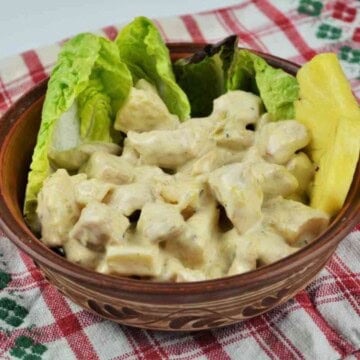 Creamy chicken breast with pineapple salad served in a ceramic bowl garnished with fresh lettuce leaves and sweet pineapple chunks.