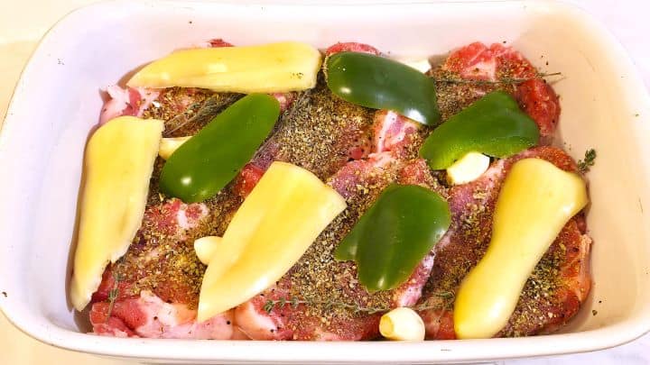 Easy Oven Baked Pork Steak Recipe-Cut Bell Peppers on Seasoned Pork Neck Slices Pepper Slices and Seasoned With Aromatic Plant Pork Shoulder Steaks in the Ceramic Tray