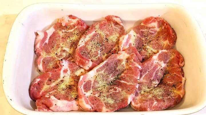 Easy Oven Baked Pork Steak Recipe-Sliced Pork Neck Seasoned With Salt and Pepper in the Tray Seasoned Pork Shoulder Steaks in the Ceramic Tray