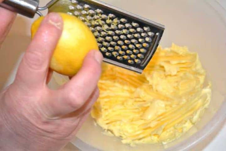 Lemon Zest Grating fresh lemon zest over softened butter in a bowl.
