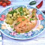 Plated spatchcock garlic butter chicken leg served with potato salad and fresh chives.