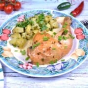 Plated spatchcock garlic butter chicken leg served with potato salad and fresh chives.
