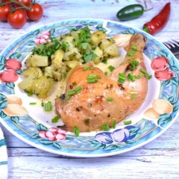 Plated spatchcock garlic butter chicken leg served with potato salad and fresh chives.