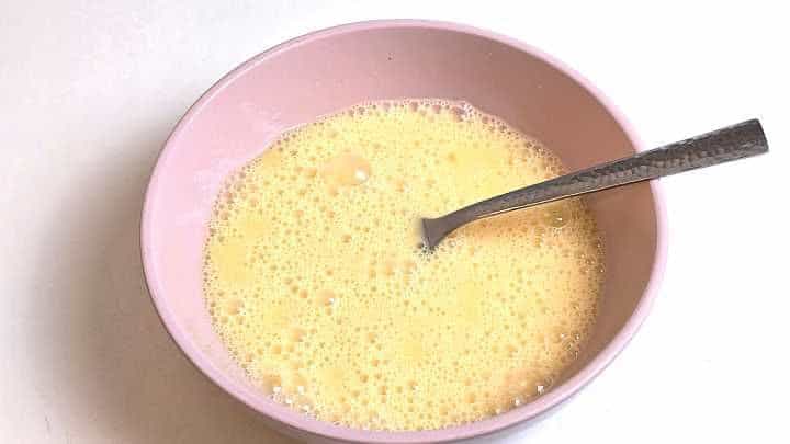 Lightly beaten free-range eggs in a ceramic bowl ready for Tojásos Lecsó.