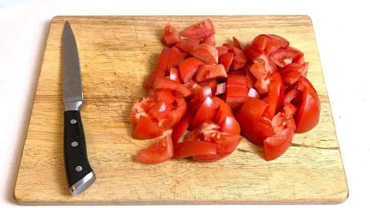 Thick wedges of ripe red tomatoes cored and prepped for simmering in Lecsó.