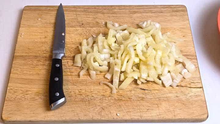 Bite-sized sliced Hungarian yellow wax peppers on a wooden chopping board.