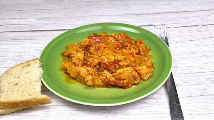 Plated Hungarian vegetable stew with eggs served with fresh crusty white bread.