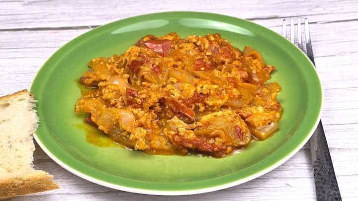 Hungarian vegetable stew with eggs served on green plate with bread.