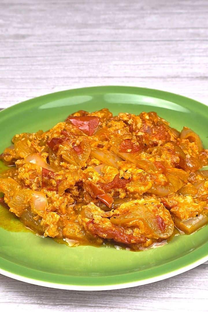 Authentic Hungarian vegetable stew with eggs (Tojásos Lecsó) served on a plate with crusty bread slices.