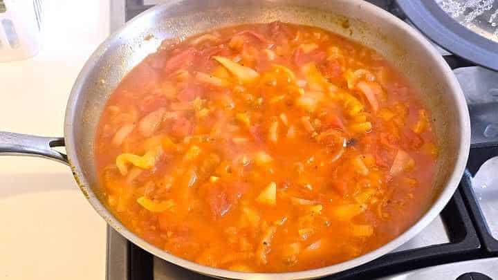 Hungarian vegetable stew simmering uncovered in a skillet until thickened.