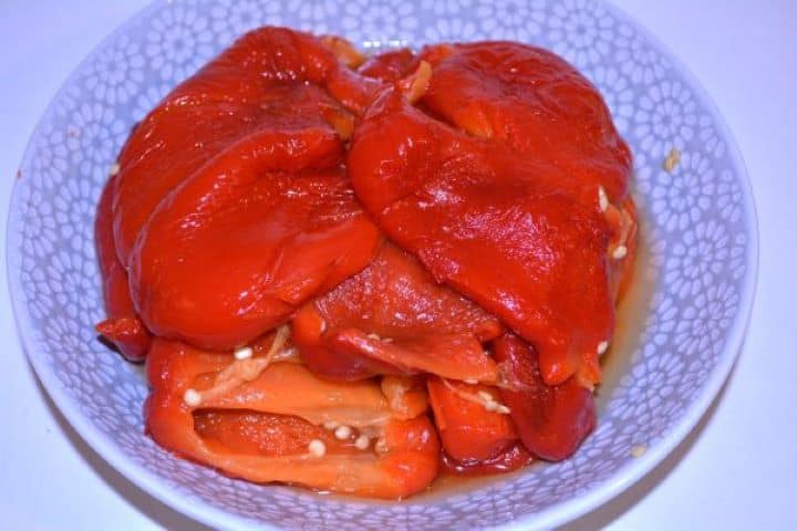 Marinated Roasted Red Peppers-Peeled Roasted Peppers in the Bowl Peeled roasted red pepper strips draining in a bowl.
