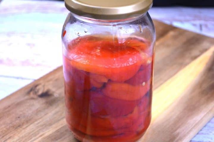 Marinated Roasted Red Peppers-Preserved in the Jar Marinated roasted red peppers preserved in a clean glass jar with liquid.