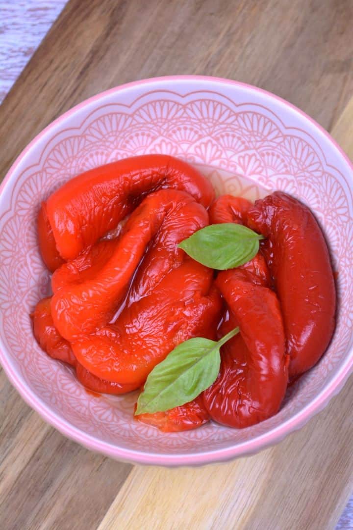 Marinated Roasted Red Peppers-Served in the Bowl Bowl of sweet and tangy marinated roasted red peppers garnished with fresh basil.