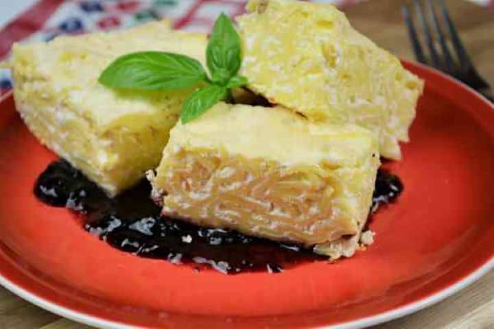 Noodle Kugel With Raisins-Served on Plate With Blueberry Jam on Bottom Sweet Noodle Kugel With Raisins Served on Plate With Blueberry Jam